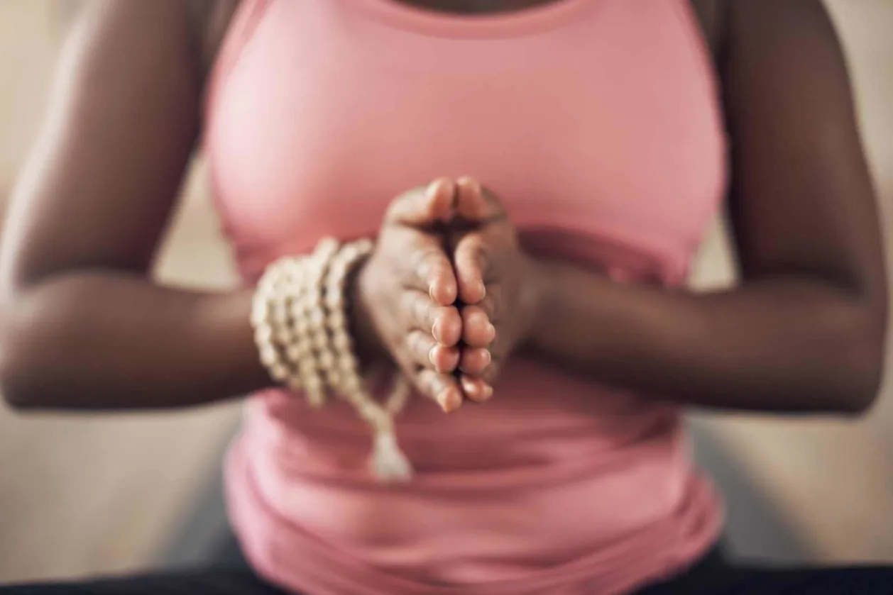Cropped image of woman using mala beads for meditation